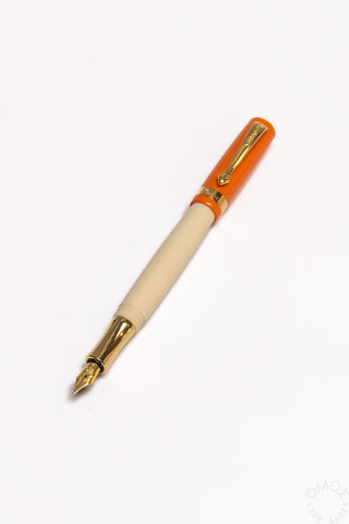 Orange student fountain pen with medium nib, beige grip section and gold accents