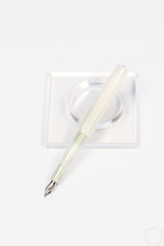 Light green fountain pen with fine nib resting in clear square holder