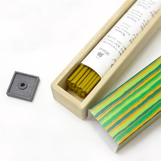 Open wooden incense box with yellow-brown sticks and a round incense holder