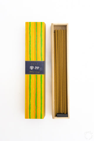 Striped incense stick box with open wooden tray and brown incense sticks