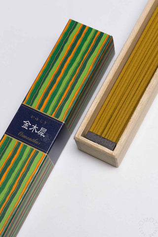 Striped incense box with exposed incense sticks in a wooden tray