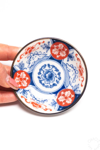 Mini plate held in hand, blue-and-red floral design with dark outer rim