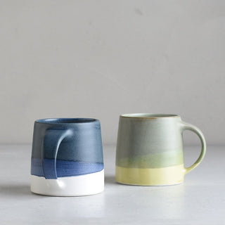 Pair of ceramic mugs: navy/white and pale green/yellow with curved handles