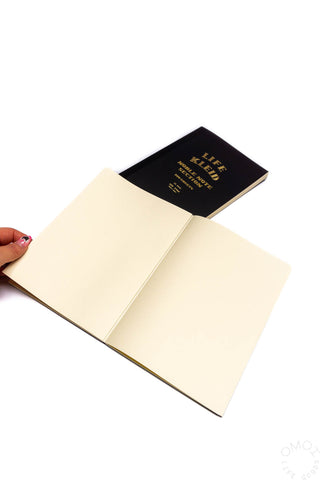 A5 notebook open with black cover and blank cream pages