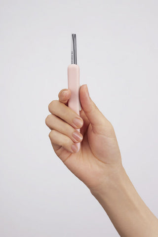 Hand holding compact scissors with light pink handle and silver blades