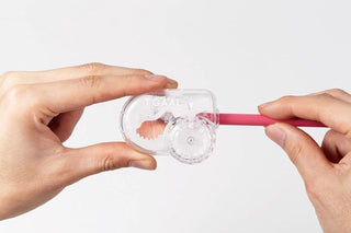Clear adjustable angle pencil sharpener with red handle held by hands