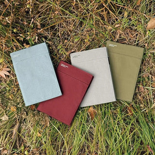 Olive, gray, and burgundy A5 notebook covers on grass with sewn pockets
