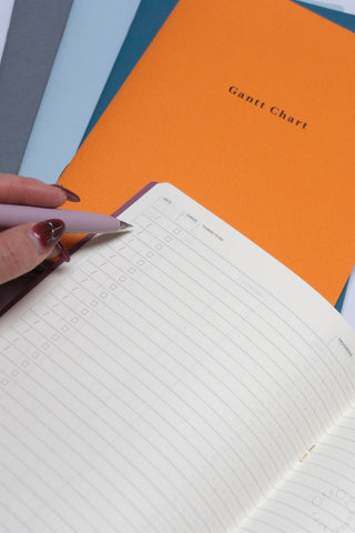 Opened notebook with orange cover and printed chart layout; hand holds page