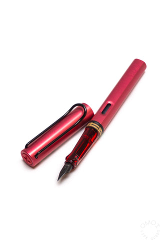 Fiery red fountain pen with fine nib, clear window, and gold accents