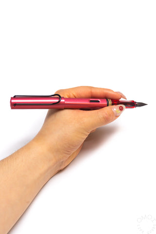 Fiery red fountain pen held in hand, side view with fine nib extended