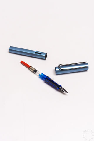 Blue fountain pen with red-capped ink converter and detached barrel