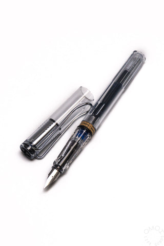 Fountain pen uncapped with fine nib, clear barrel, black grip and metal clip