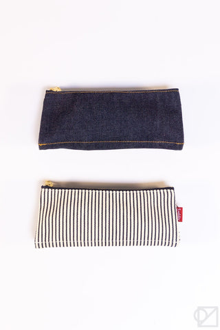 Two pen cases: dark denim pouch and black-and-cream striped pouch with gold zipper