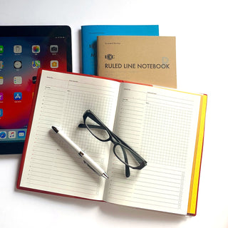 Open A5 ruled line notebook with grid layout, pen, and eyeglasses on the pages.