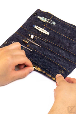 Denim patchwork 5-slot pen case with gold zipper and stitched pen holders, hands showing interior