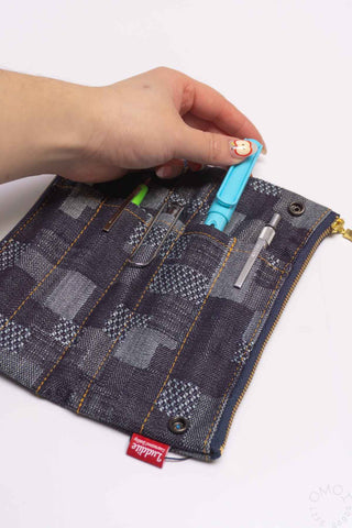 Dark denim patchwork pen case pouch held in hand, gold zipper and pen compartments