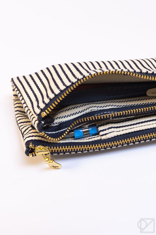Striped pen case pouch open, showing gold zipper track and inner pen compartments