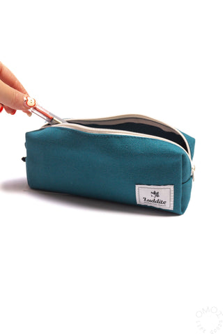 Teal box pen case with zipper open while a hand pulls out a pen