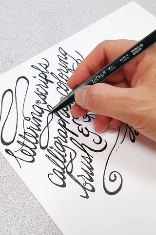 LePen Flex brush marker in hand, writing cursive on white paper