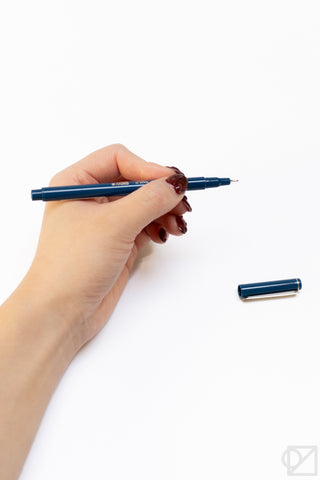 Hand holding a dark blue Le Pen-style pen with silver tip and clip.