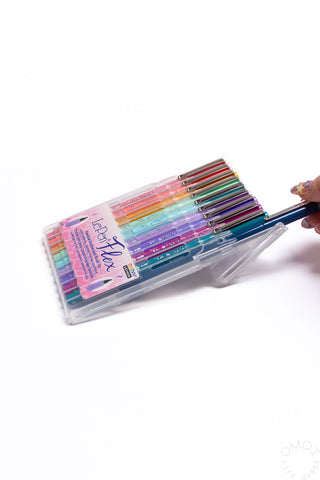 Pastel brush pen set in clear case with pens visible, hand lifting one marker