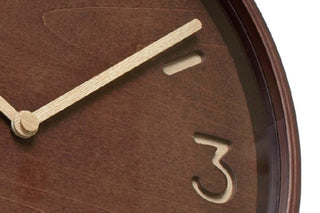 Close-up of brown clock dial with gold hour marker and slender clock hands