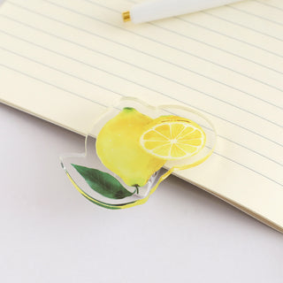 Lemon fruit acrylic clip fastening a notebook page, yellow lemon wedge with slice