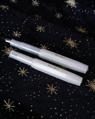 Light green fountain pens with fine nibs, two on dark fabric with snowflakes
