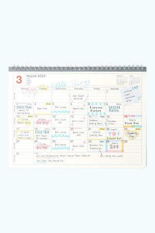 2027 monthly notebook calendar page with colorful blocks and spiral binding