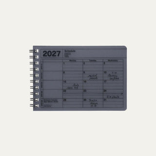 Navy 2027 notebook calendar cover showing a weekly schedule page and spiral rings