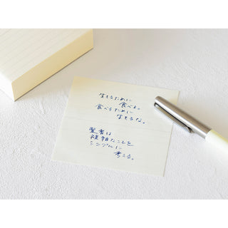 Lined memo sheet with blue handwritten notes and silver pen