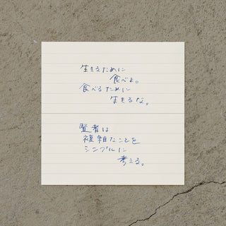 Lined memo sheet on concrete with blue and black handwritten notes