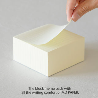 Cream lined memo pad with a sheet being lifted by hand