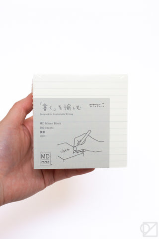 Hand holding lined memo pad block with gray product label