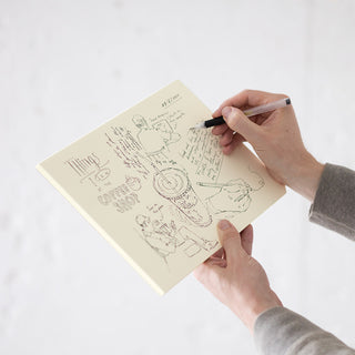 Cotton paper pad with open pages of line art, held by hands