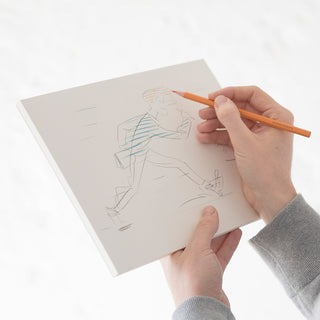 Cotton paper pad with sketch lines on open sheet, hands drawing with pencil