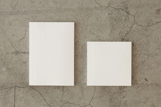 Two cotton notebooks with plain cream covers, one larger and one smaller.