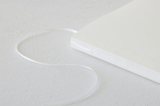 White cotton notebook cover with textured fabric and attached elastic cord loop