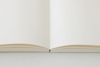 Opened white cotton notebook showing inner pages and spine crease