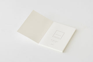 MD Cotton notebook, open with cream pages and a small line-art logo on the cover.