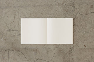 Cotton notebook open with two blank cream pages and a center fold.