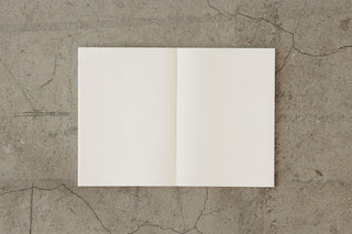 Cotton notebook open with two blank cream pages in a simple centered spread.