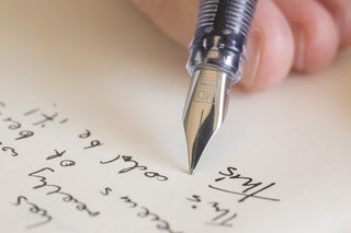 Close-up of fountain pen nib writing on paper with dark ink
