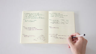 MD 2027 monthly planner notebook open spread with printed instructions and pen writing