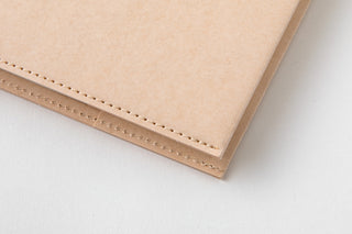 Close-up of beige notebook cover edge with stitched border