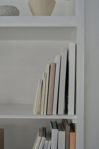 Stack of cream notebooks with dot grid pages visible on a shelf