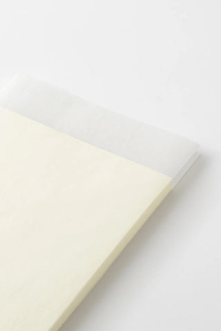 Cream notebook lying angled with smooth cover and visible book edge