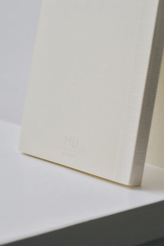 Cream notebook back cover corner with subtle MD logo emboss