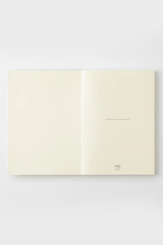 Cream dot grid notebook opened, right page shows small MD logo