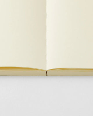 Open notebook view with cream pages and yellow-gold page edges at spine.